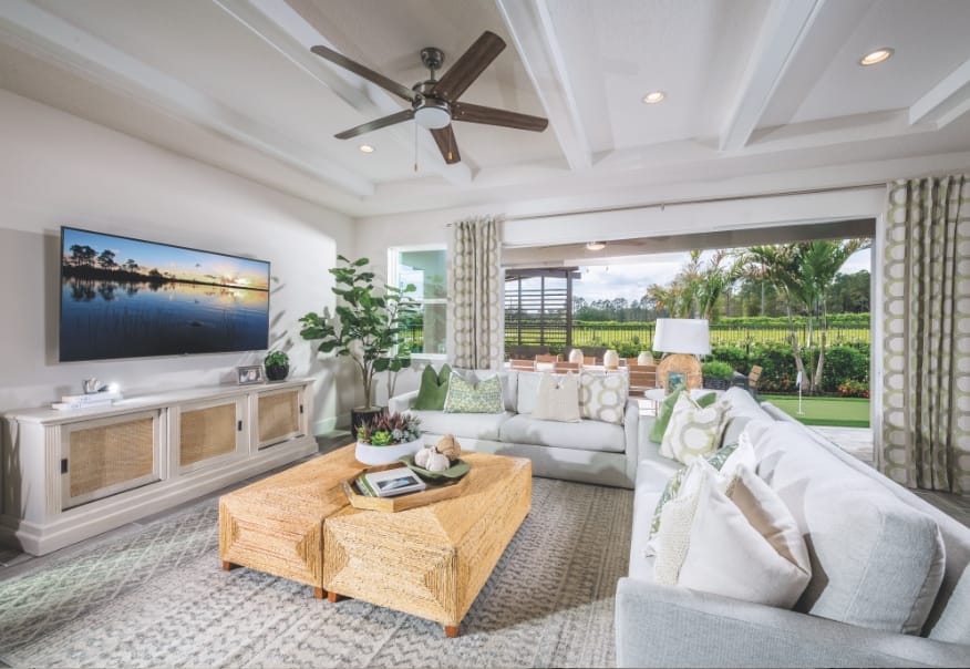 The interior of a home, showing the living room with floor-to-ceiling windows that lead out to the back patio in Sunbridge community, St. Cloud, Florida in Metro Orlando