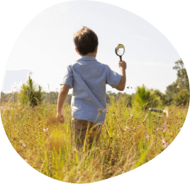 Young boy playing in a field with a magnifying glass in Sunbridge community, St. Cloud, Florida in Metro Orlando