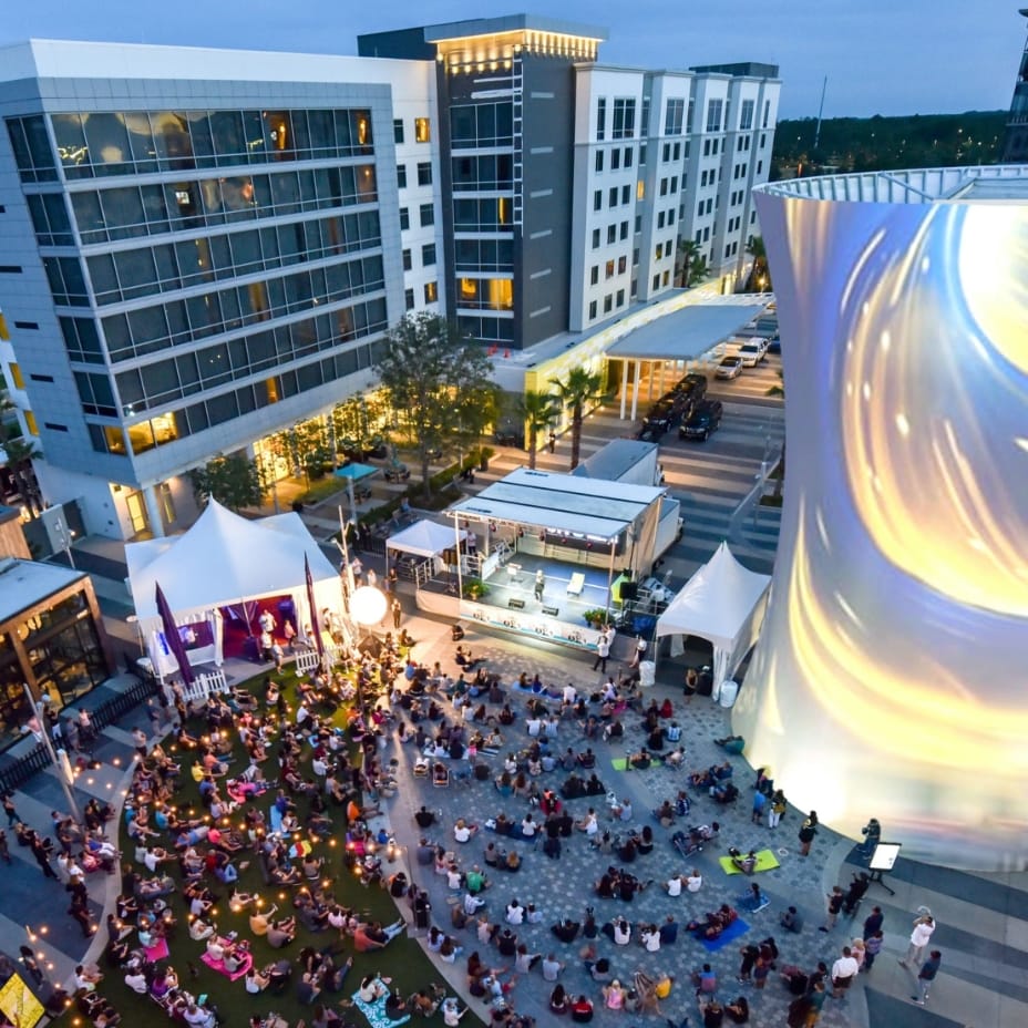A birds-eye-view of the Lake Nona Town Center, with a large crowd of people attending a concert.