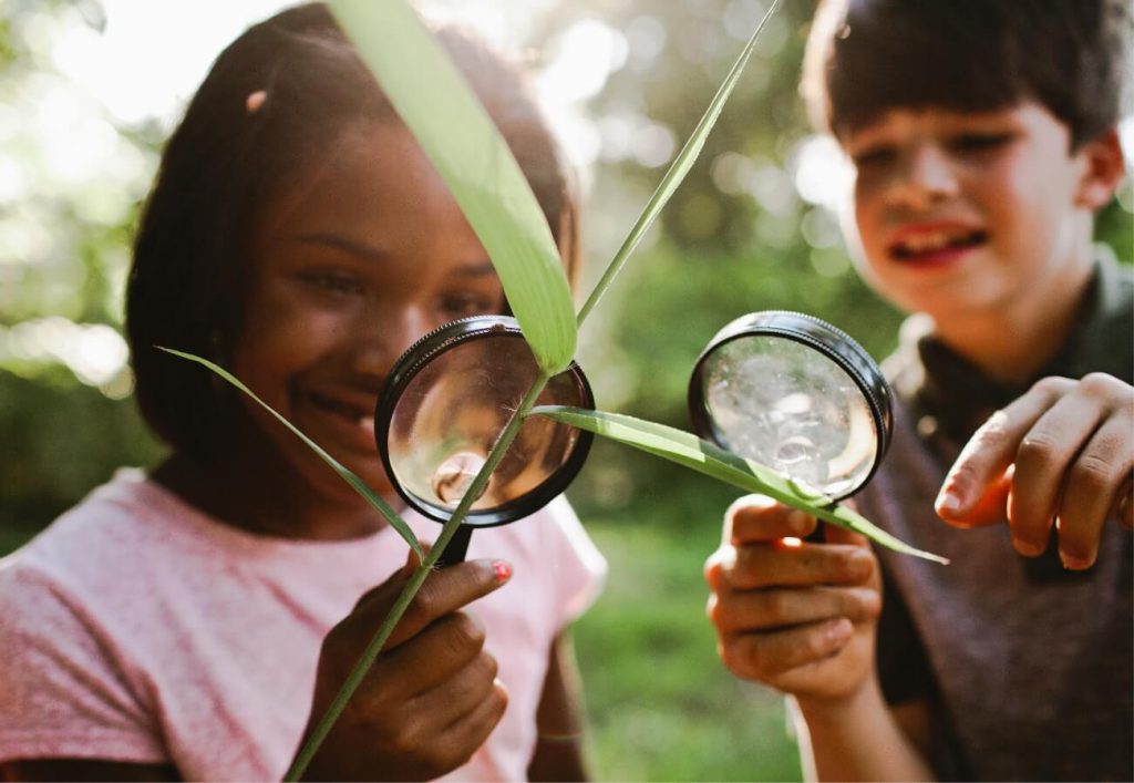 Young girl looking at a plant with a magnifying glass in Sunbridge community, St. Cloud, Florida in Metro Orlando