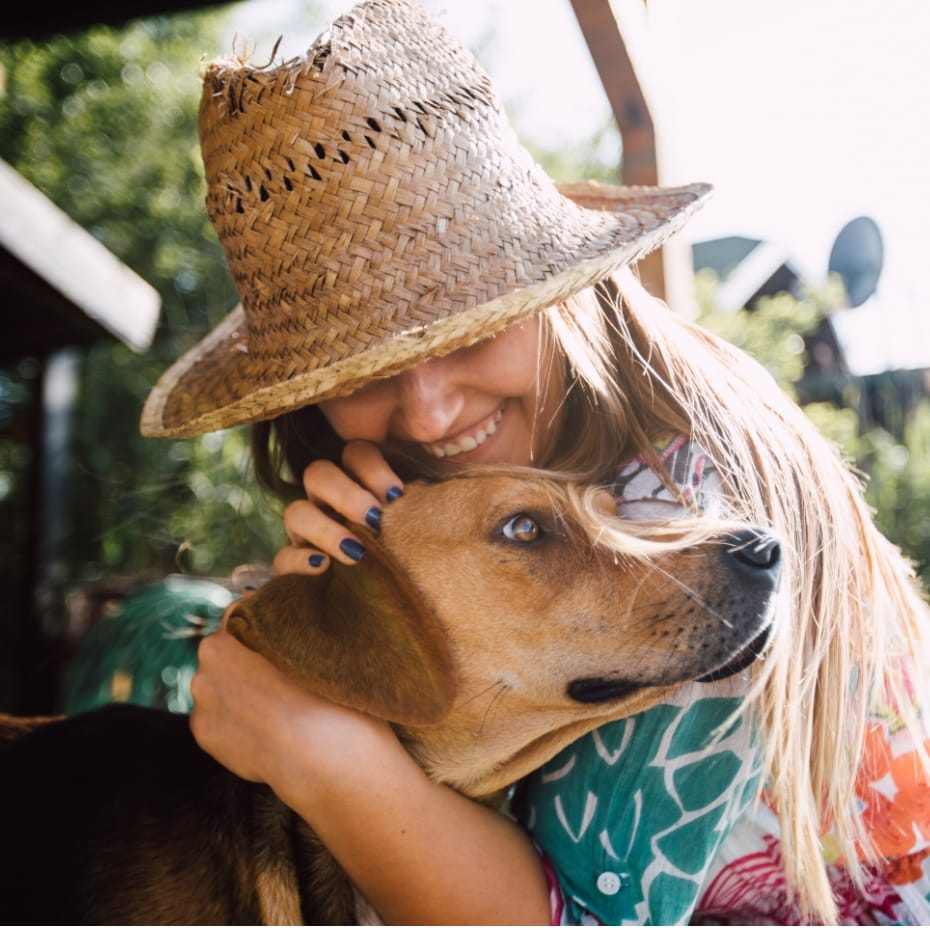 Woman wearing a straw hat and hugging her dog in Sunbridge community, St. Cloud, Florida in Metro Orlando