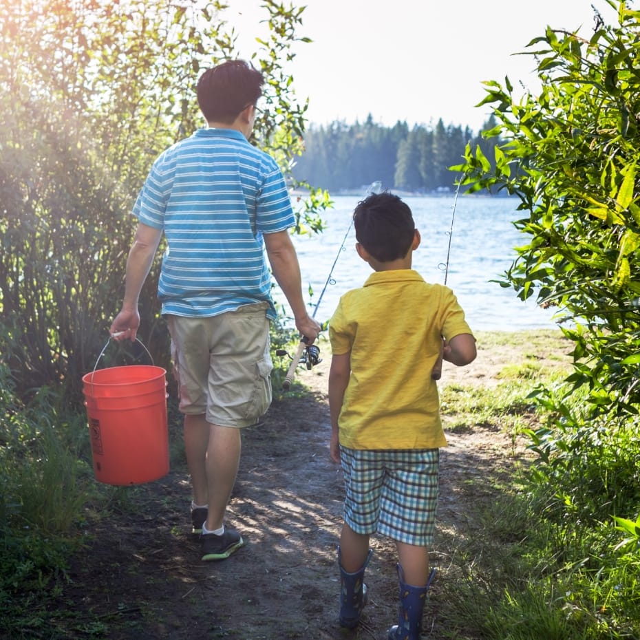 Older boy and younger boy carrying a bucket and fishing poles towards a lake in Sunbridge community, St. Cloud, Florida in Metro Orlando