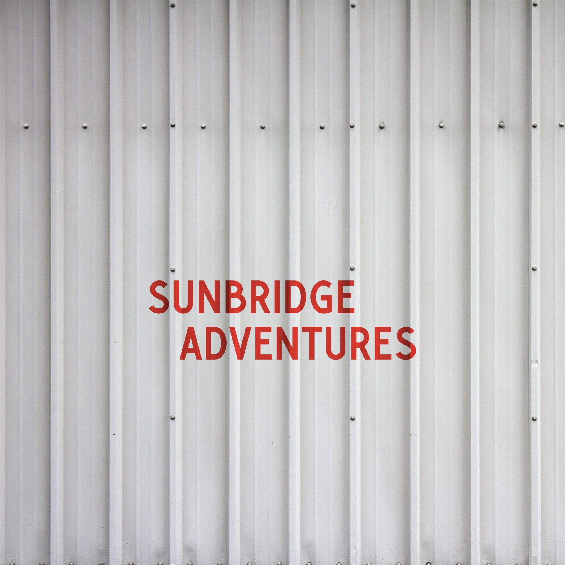 The logo of Sunbridge Adventures painted in red on a light grey metal wall