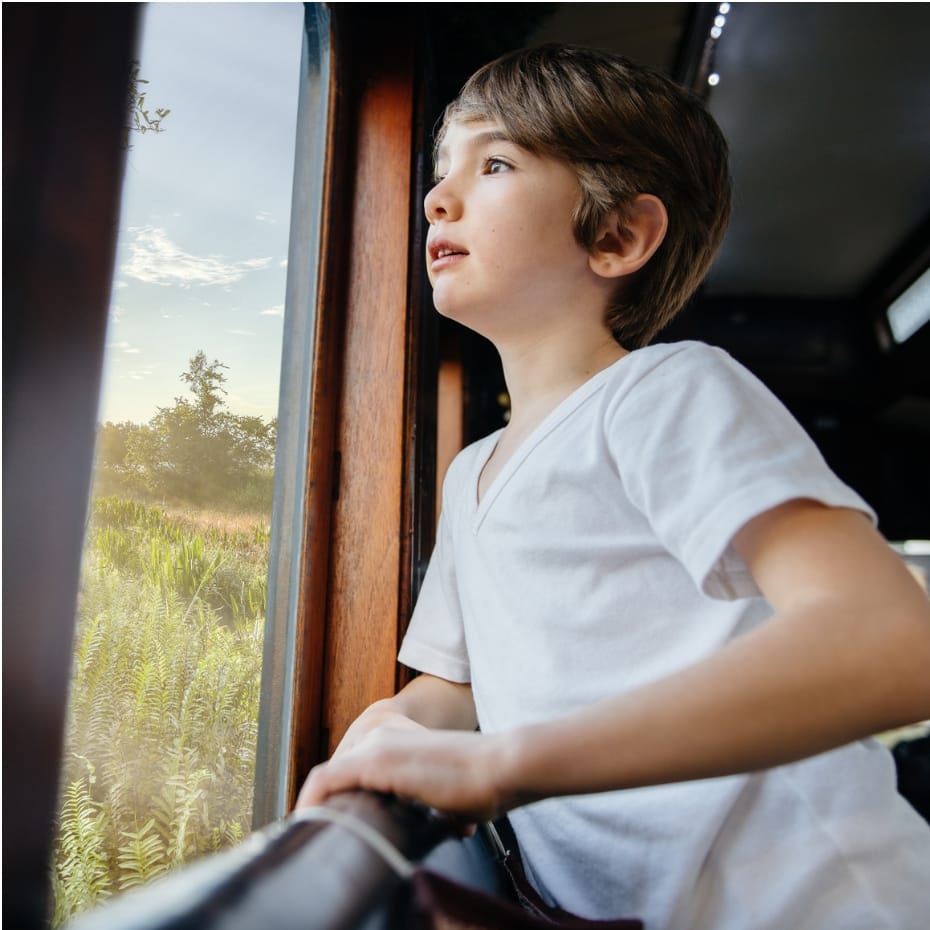 A young boy looking out of the window of a train