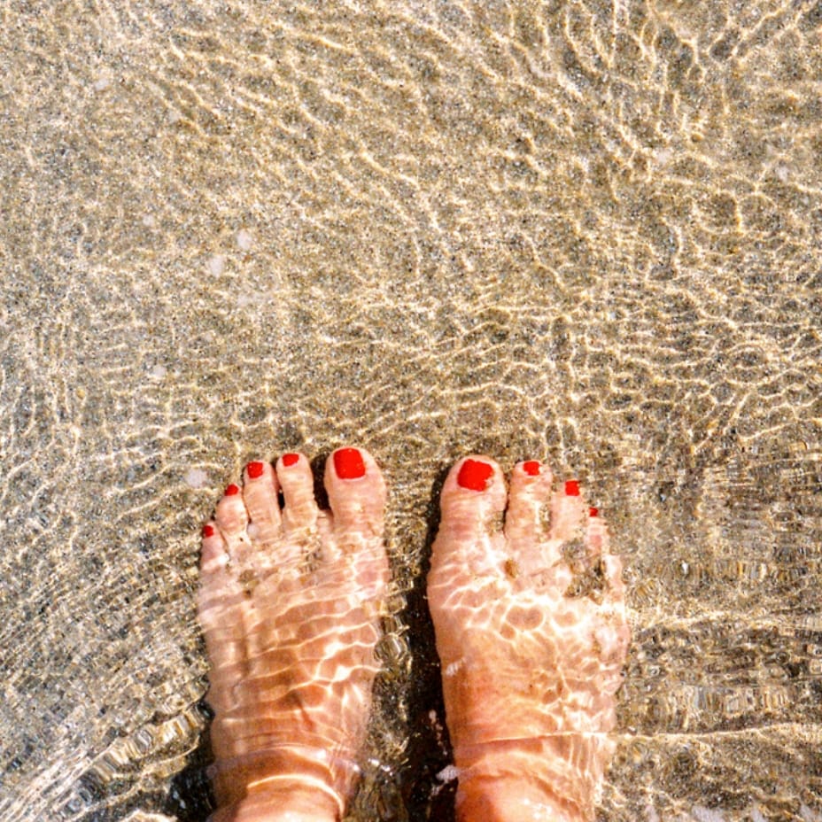 Feet with red nail polish standing in the water at a beach in Sunbridge community, St. Cloud, Florida in Metro Orlando