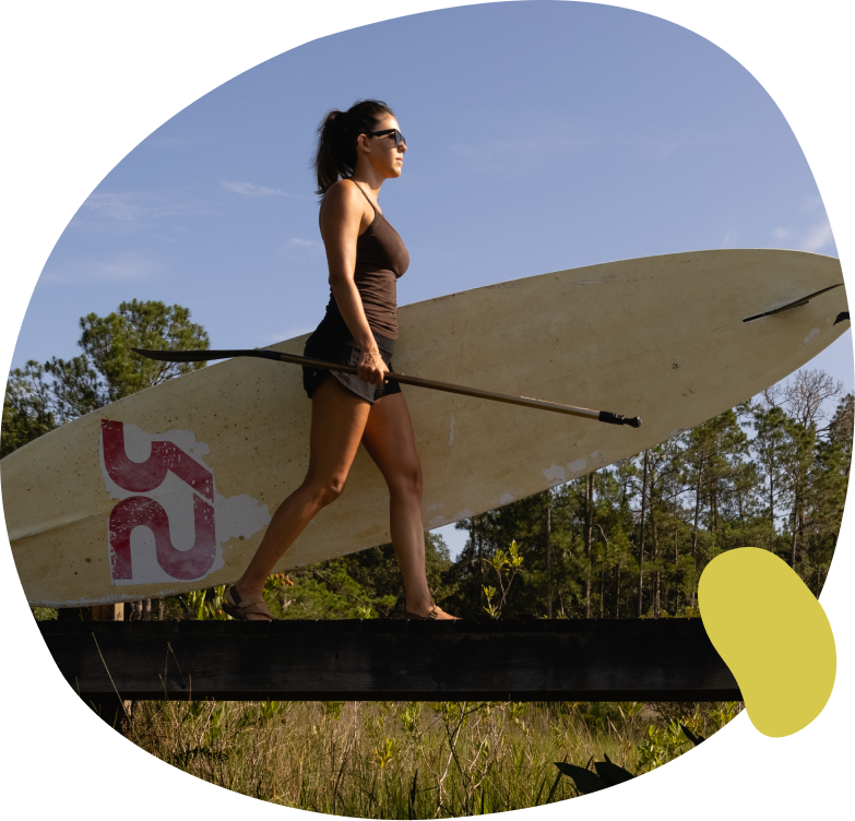 Woman walking along a pier while carrying a stand-up paddleboard and oar in Sunbridge community, St. Cloud, Florida in Metro Orlando